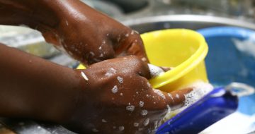 closeup-shot-black-female-hand-washing-yellow-bowl (1)